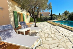 A poolside area with lounge chairs and a stone-tiled patio.