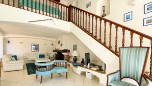 A spacious living room with a high wooden staircase, a sofa set, a patterned rug, and a blue armchair. - Villa 10 people-Private Pool-250m from the sea (Fréjus)