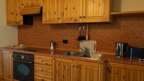 A kitchen with wooden cabinets, a stainless steel sink, a stove, and a toaster.