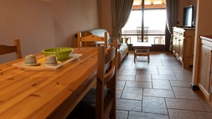A cozy room with a wooden dining table, a bunk bed, and a TV on a cabinet.