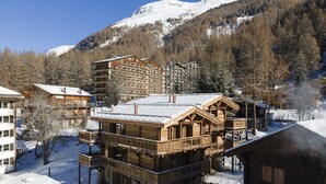 A wooden lodge with multiple balconies and a ski lift in the background.