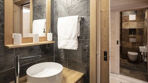 A modern bathroom with a round sink, a mirror, and a towel rack.
