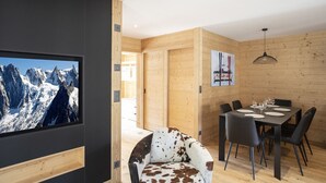 A modern interior with a wooden dining area, a mounted TV, and a cowhide chair.