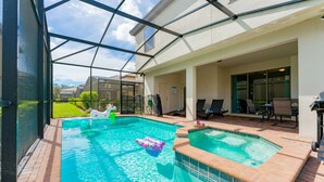 Una piscina con cerramiento de vidrio, un jacuzzi y zona de estar exterior.