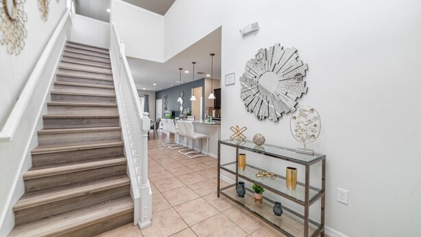 Un interior moderno con una escalera, una consola de vidrio y decoración en la pared.