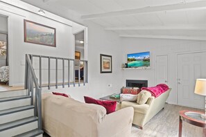 Un salon avec un canapé beige, une table basse, un téléviseur et une cheminée.