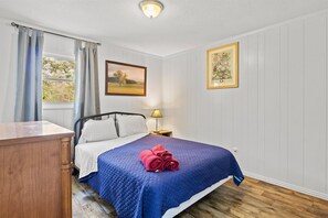 A bedroom with a bed, a nightstand, a lamp, and a window with curtains.