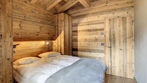 Ein Zimmer in einer Holzhütte mit einem Bett, einem Nachttisch und einer Tür.