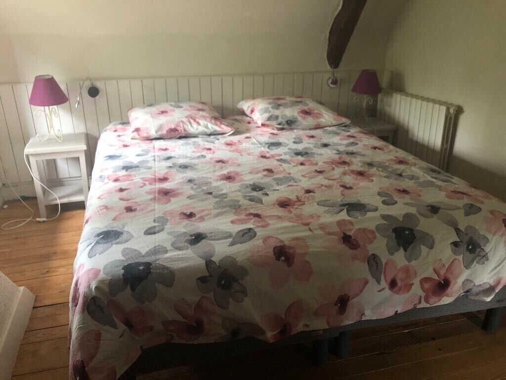 A bedroom with a floral bedspread, two bedside lamps, and a wooden floor.