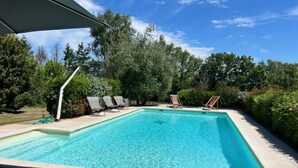 A rectangular swimming pool with clear blue water, surrounded by lounge chairs and a covered area. - Authentic Quercy house, between Périgord and Quercy (Peyrilles)