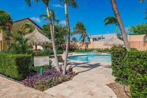A pool area with lounge chairs, palm trees, and a signboard.