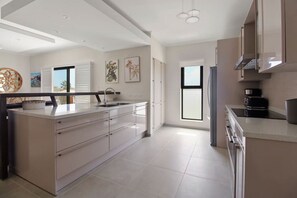 Een moderne keuken met een centraal eiland, roestvrijstalen apparatuur en een groot raam voor natuurlijk licht.
