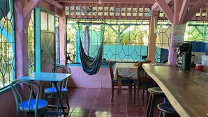 A covered patio area with tiled flooring, tables, chairs, and a hammock. - Hidden Jungle Beach House, a Unique Guesthouse in Puerto Viejo de Talamanca!  (Puerto Viejo de Talamanca)