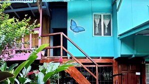 A two-story building with a blue exterior, a wooden staircase, and a butterfly mural. - Hidden Jungle Beach House, a Unique Guesthouse in Puerto Viejo de Talamanca!  (Puerto Viejo de Talamanca)