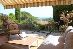 A patio with a hammock, a chair, and a table.