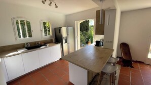 Een moderne keuken met witte kasten, een groot eiland en uitzicht op groen.