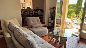 Een woonkamer met een bank, fauteuils en een glazen salontafel.