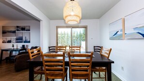 Un espace repas comprenant une grande table, des chaises en bois et un luminaire suspendu.