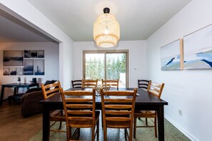 Uma área de refeições com uma mesa grande, cadeiras de madeira e um lustre.