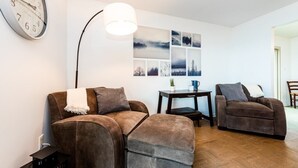 Un salon avec deux canapés marron, une table basse, une lampe et une horloge murale.