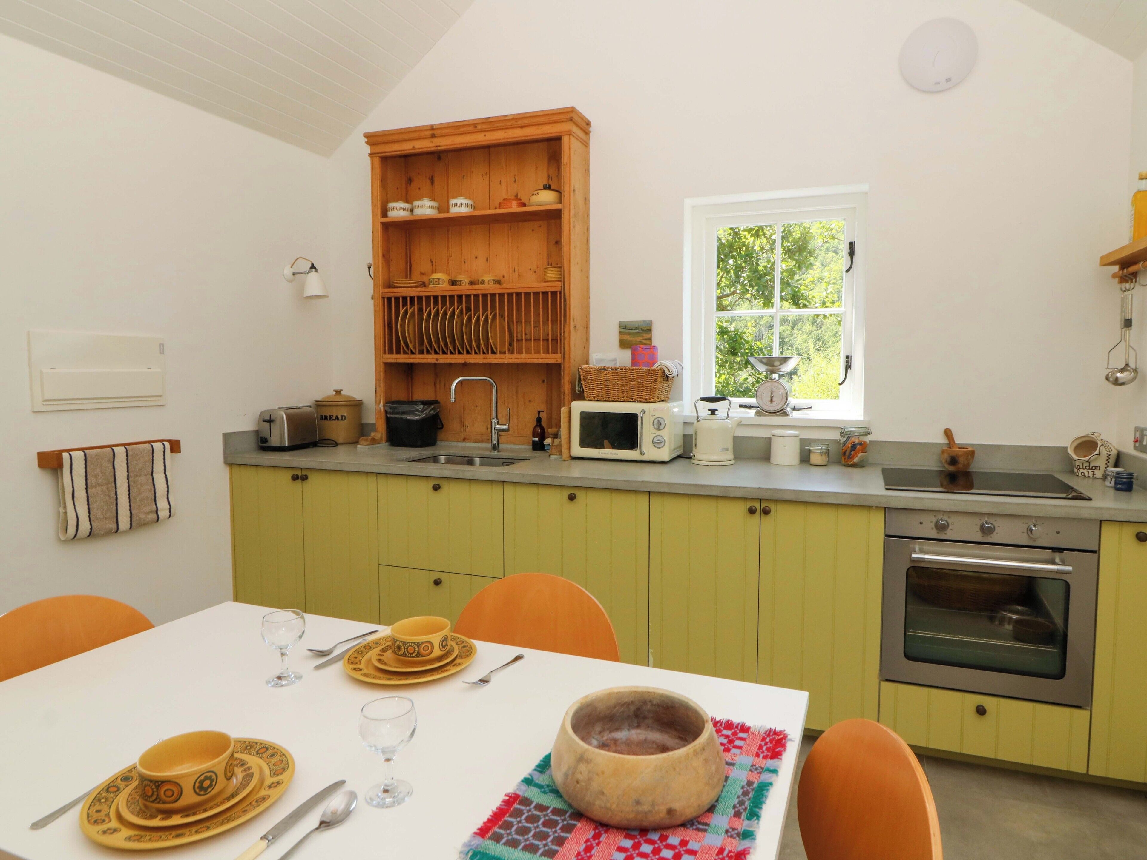 A kitchen with a wooden cabinet, a window, a sink, a microwave, and a stove.