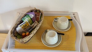 A tray with two white cups and saucers, a wicker basket containing various food items, and a yellow woven placemat. - BLU Flat (2 pax) + 2 Bunks Bed, FIOCCHINA magic place - Salò - Garda Lake (Lombardia)