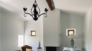 Een woonkamer met een open haard, twee banken, een salontafel en een kroonluchter.