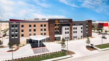 A modern hotel with a central entrance, multiple floors, and a parking area.