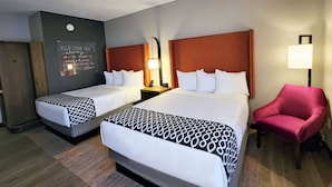 A hotel room with two beds, a red armchair, a wall-mounted light, and a motivational quote on the wall. - La Quinta Inn & Suites By Wyndham Pflugerville (Pflugerville)