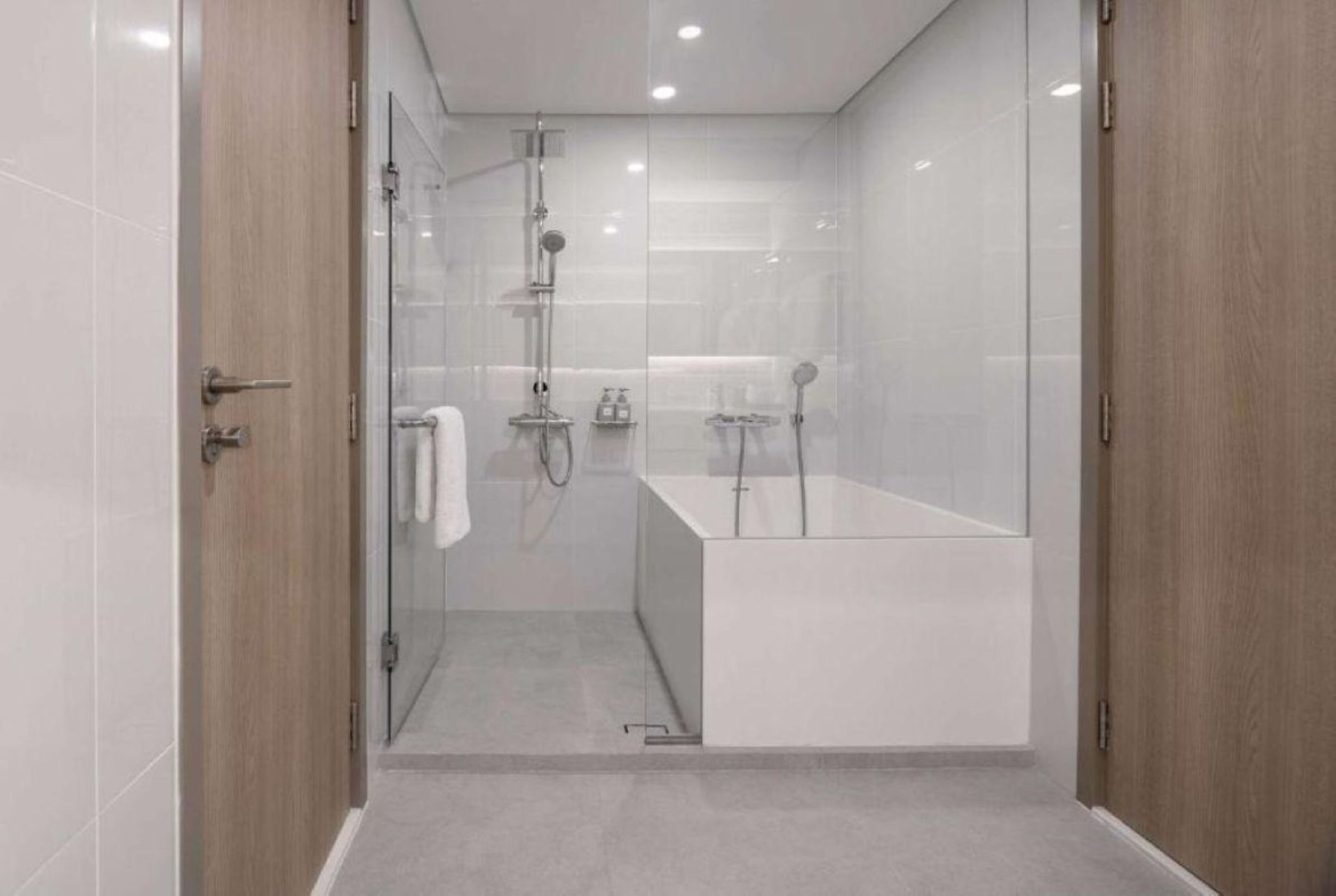 Une salle de bain moderne avec une douche à parois de verre, un lavabo blanc et une porte en bois.