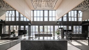 A modern kitchen with a marble island, large windows, and a high ceiling with a unique light fixture. - Ramada by Wyndham Bangkok Sukhumvit 87 (Bangkok)