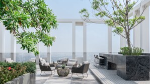 Terraza en la azotea con mobiliario exterior, zona de comedor y vistas a la ciudad.