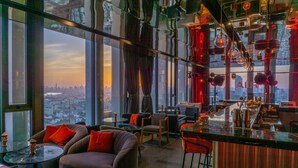 A modern bar area with seating, large windows, and a city view. - Ramada by Wyndham Bangkok Sukhumvit 87 (Bangkok)