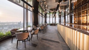 A modern restaurant with large windows offering city views, stylish chairs, and unique hanging light fixtures. - Ramada by Wyndham Bangkok Sukhumvit 87 (Bangkok)