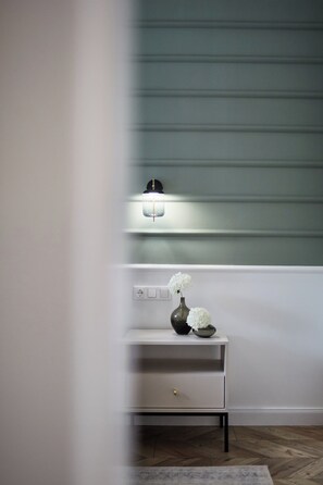 A minimalist room with a white console table, a vase with white flowers, and a wall-mounted light fixture.