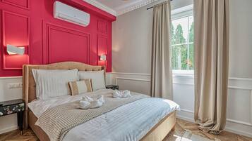 A hotel room with a bed, a nightstand, a window with curtains, and a wall-mounted air conditioner.
