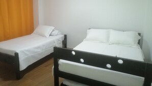 A room with two single beds, a wooden headboard, and an orange curtain. - San Andrés Central Apartment 10 (San Andrés)