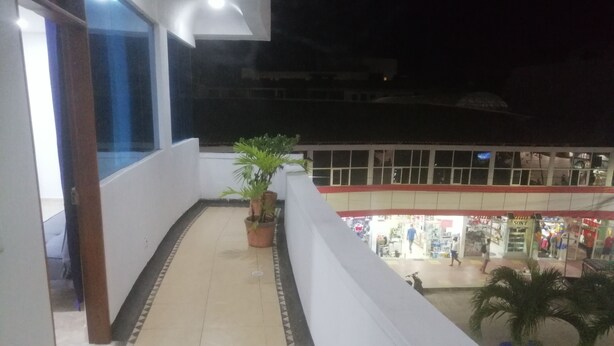 A balcony with a tiled floor, potted plants, and a view of a shopping area with a Sony store. - San Andrés Central Apartment 10 (San Andrés)