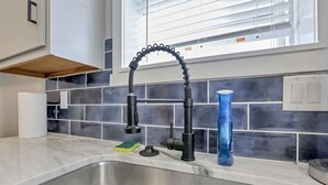 A kitchen with a stainless steel sink, a modern faucet, and a blue water bottle on the counter. - Nostalgic in Nelsonville: Great back yard for pets (Nelsonville)