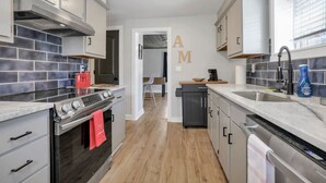 A modern kitchen with grey cabinets, a stainless steel stove, and a wooden floor. - Nostalgic in Nelsonville: Great back yard for pets (Nelsonville)