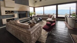 A spacious living room with a fireplace, a large sofa, red chairs, and a view of the mountains through large windows. - Rest house in Yerbabuena (Sopo)