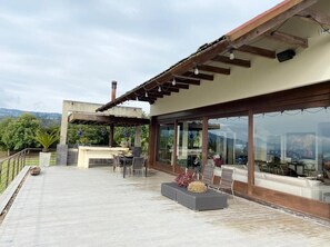 Un patio moderno al aire libre con terraza de madera, zona de estar y espacio cubierto con vidrio.