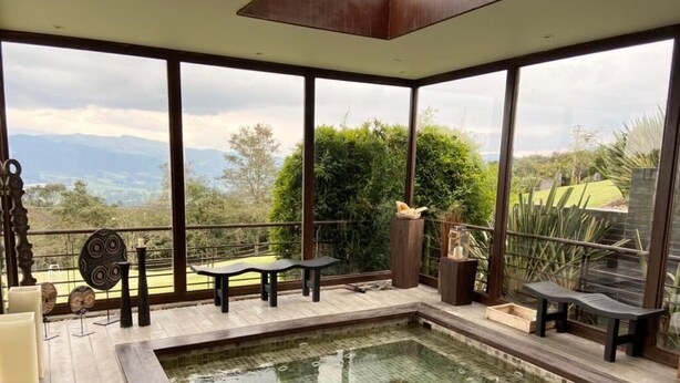 A pool area with a view of mountains, a wooden deck, and outdoor furniture. - Rest house in Yerbabuena (Sopo)