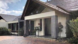 A modern house with a brick driveway, large windows, and a covered porch area. - Rest house in Yerbabuena (Sopo)