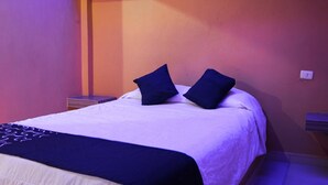 A neatly made bed with a white and dark blue bedspread, two dark blue pillows, and a dark blue throw blanket. - OYO Hotel Oasis, Monterrey (Monterrey)