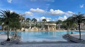 Ein Pool mit klarem, blauem Wasser, umgeben von Palmen und Felsformationen.