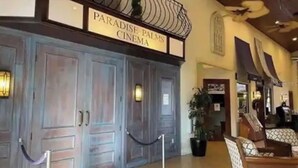 Een bioscoop met een bord waarop staat 'Paradise Palms Cinema' en een houten deur.
