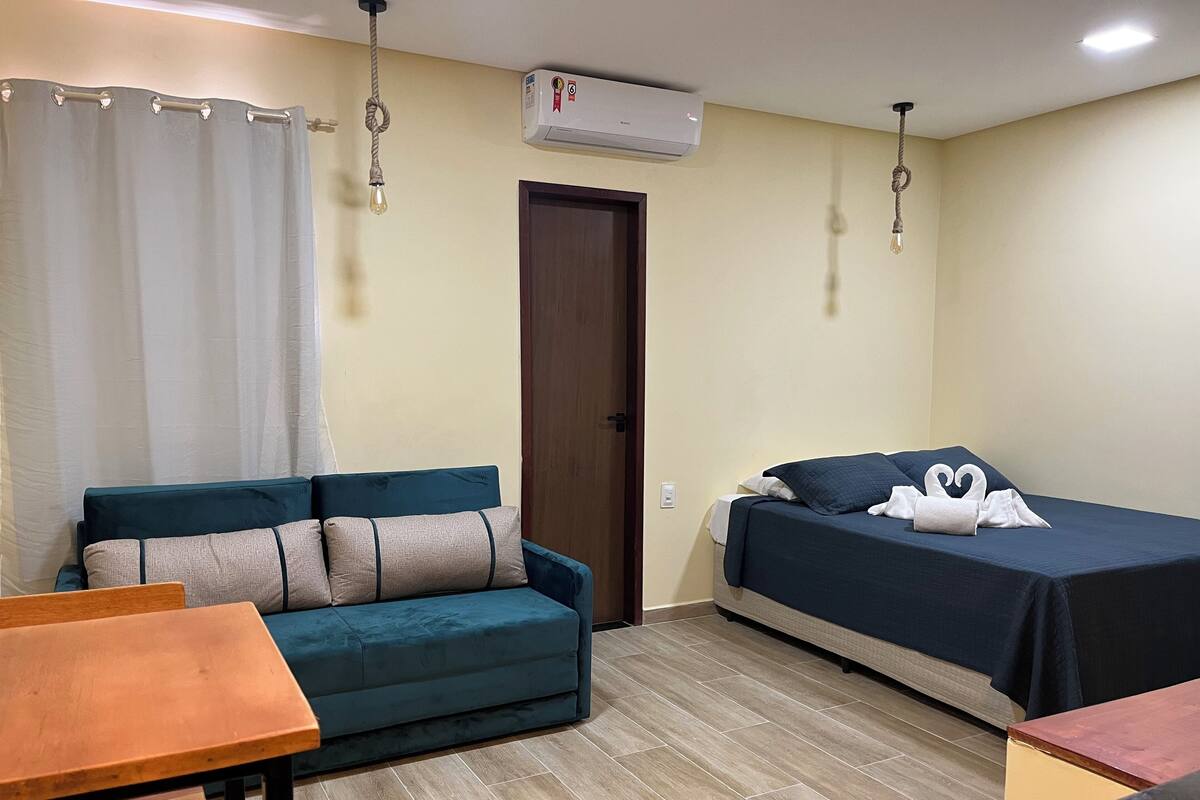 Une pièce comprenant un canapé, un lit, une table en bois et un appareil de climatisation.