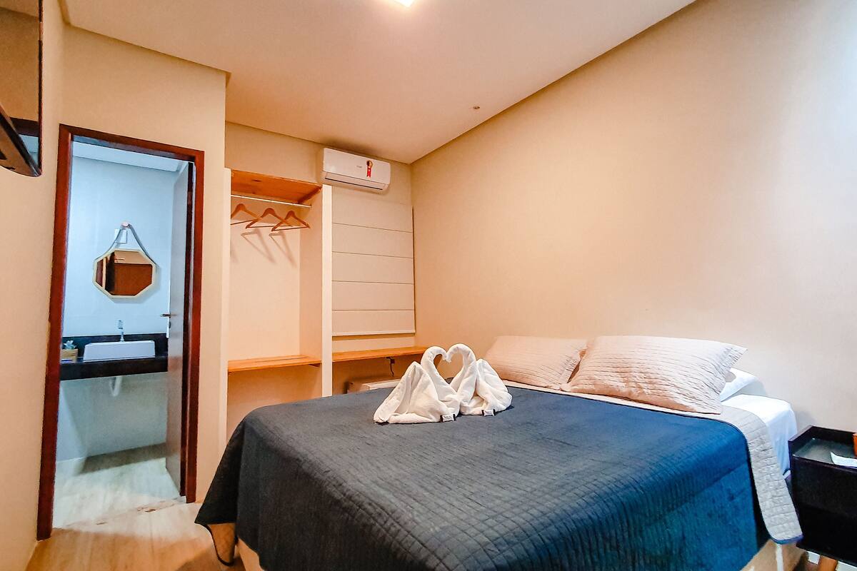 Une chambre à coucher comprenant un lit, une table de chevet avec une plante, une armoire et un appareil de climatisation.
