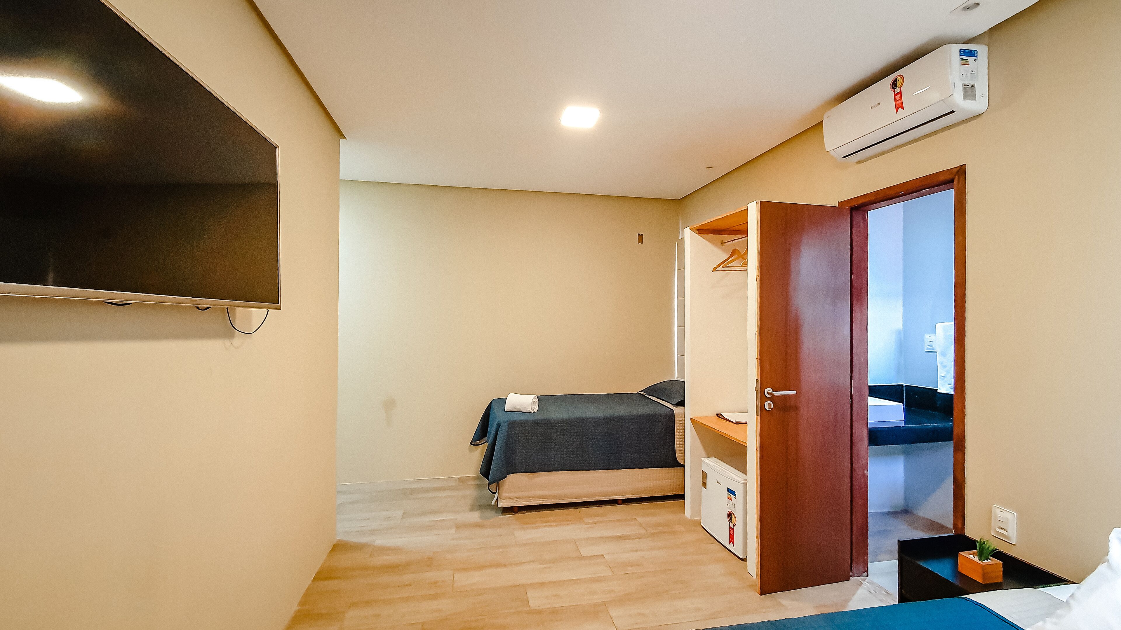 Habitación pequeña con cama, un escritorio, un armario y aire acondicionado.